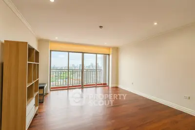 Spacious living room with hardwood floors and city view balcony.