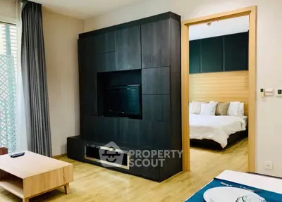 Modern living room with sleek entertainment unit and view into cozy bedroom