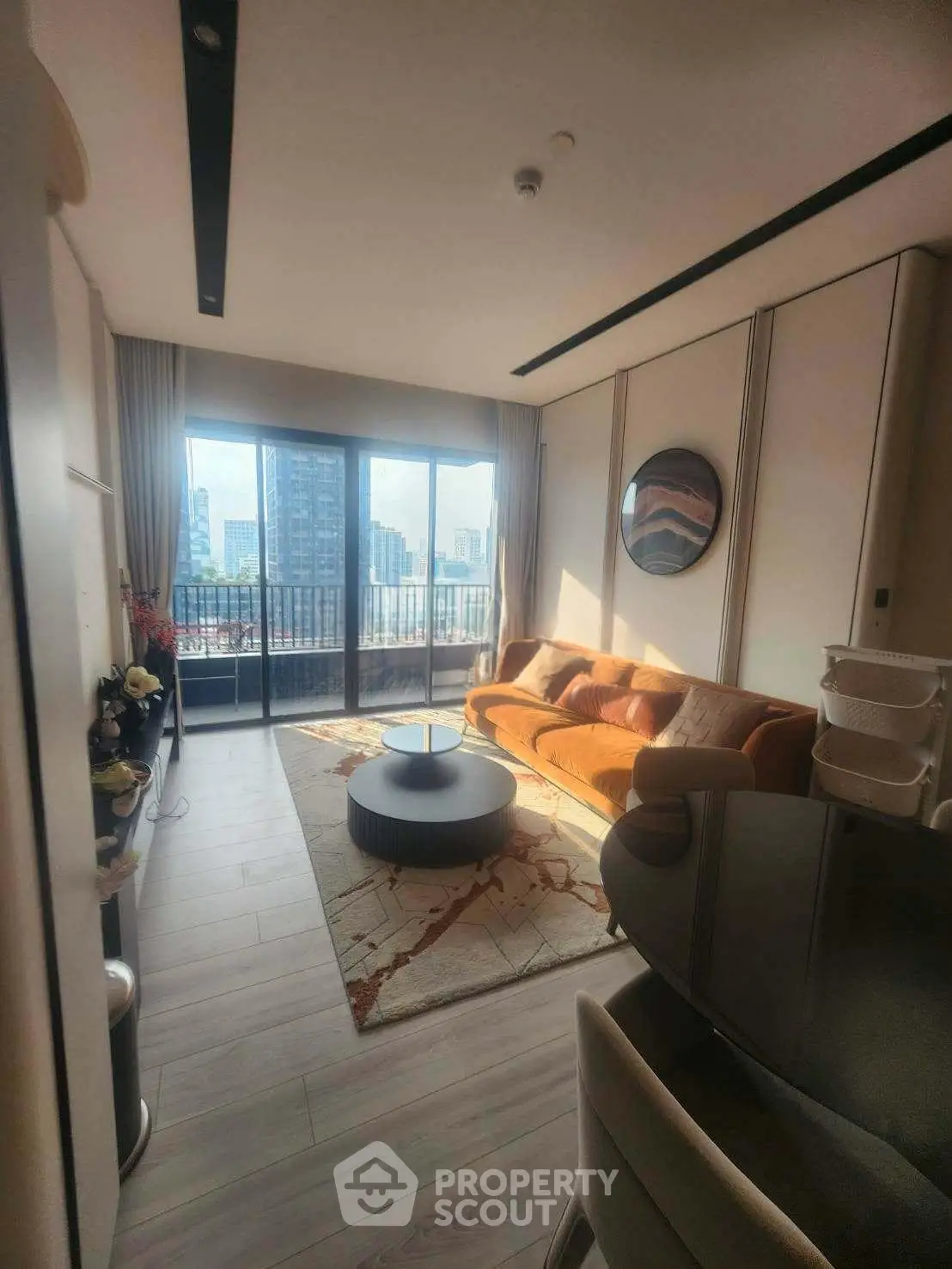 Modern living room with large windows and city view, featuring stylish furniture and elegant decor.