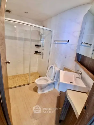 Modern bathroom with glass shower and sleek fixtures in contemporary apartment.