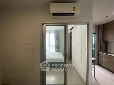 Modern apartment interior with bedroom and kitchen, featuring sleek design and air conditioning.