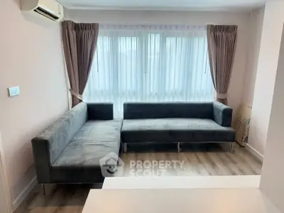 Modern living room with stylish gray sofas and large window, featuring elegant curtains and wooden flooring.