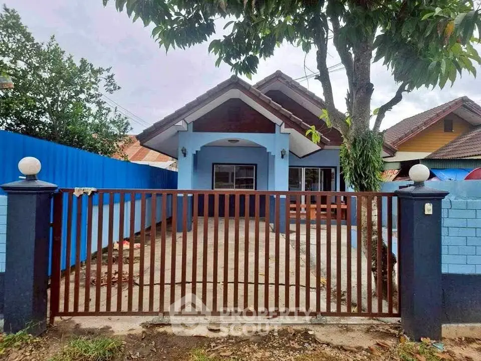 Charming blue house with gated entrance and lush greenery