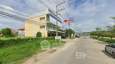 Commercial building on a busy street with lush greenery and clear skies.