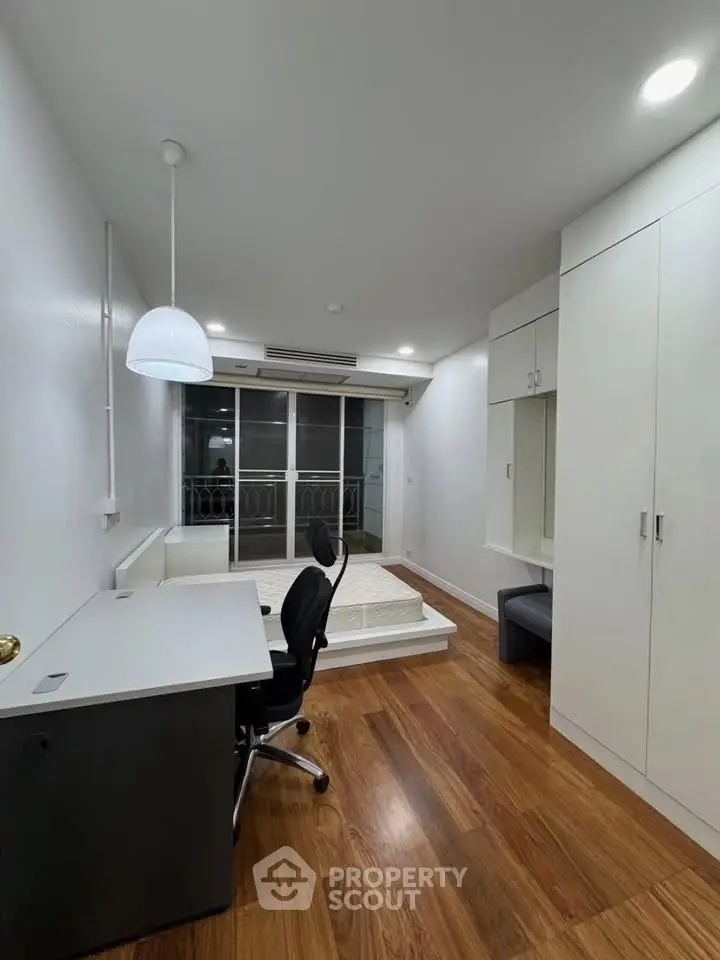 Modern study room with sleek desk, chair, and built-in storage, featuring hardwood floors and bright lighting.