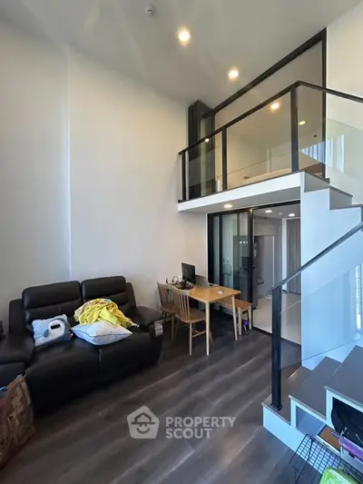 Modern loft-style living room with high ceiling and mezzanine, featuring sleek furniture and elegant design.
