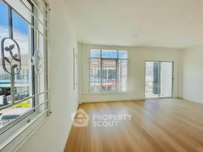 Spacious and bright living room with large windows and wooden flooring.