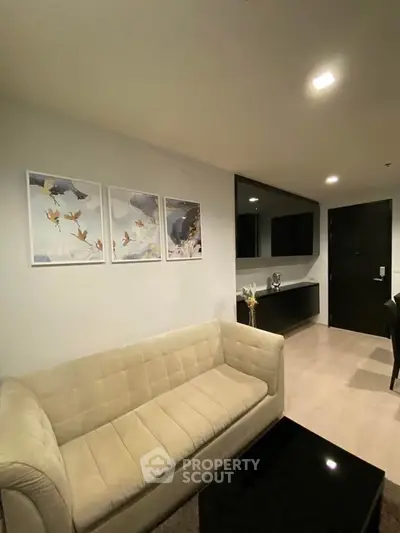 Modern living room with beige sofa, elegant wall art, and sleek black cabinetry.