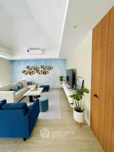 Stylish modern living room with blue accents and wall art, featuring a cozy seating area and sleek TV setup.