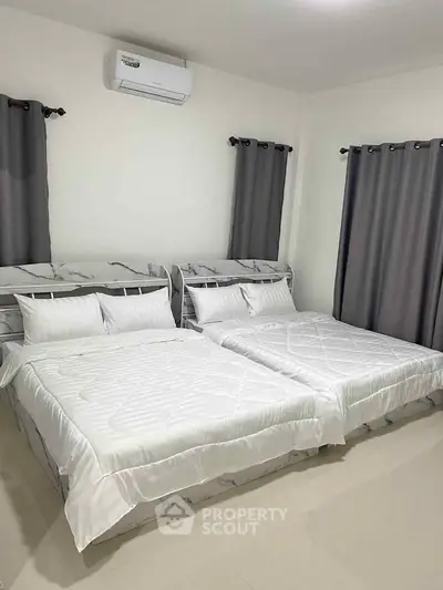 Spacious bedroom with two beds and modern air conditioning