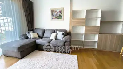 Spacious living room with cozy gray sectional sofa and modern shelving unit, perfect for relaxation.