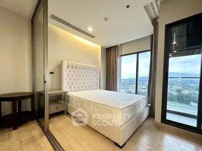 Modern bedroom with large windows offering stunning city views and elegant furnishings.