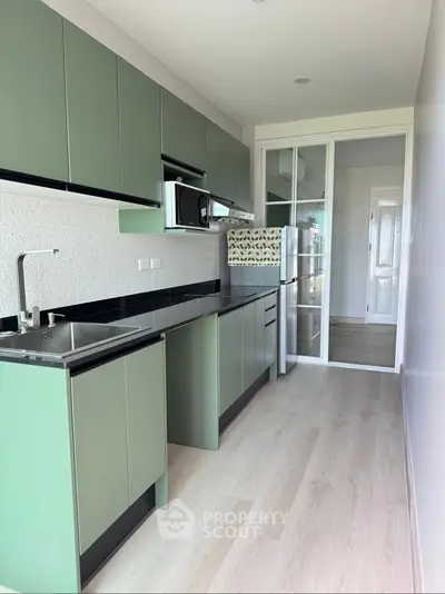 Modern green kitchen with sleek cabinets and stainless steel appliances