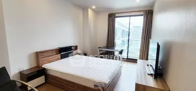 Modern bedroom with large window and stylish furniture in urban apartment