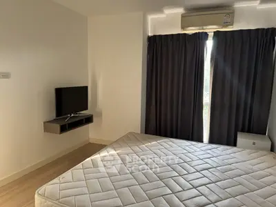 Modern bedroom with natural light, featuring a mounted TV and air conditioning.