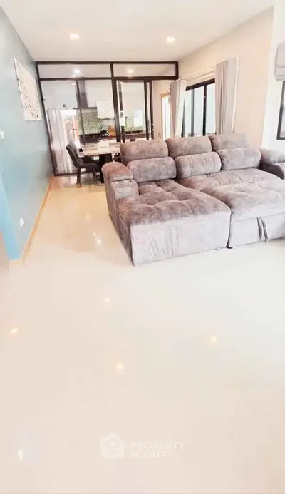 Spacious living room with plush sectional sofa and open dining area in modern apartment.