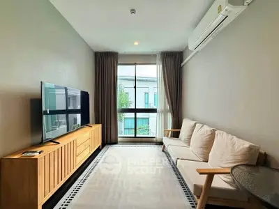 Modern living room with large window, cozy sofa, and sleek TV setup in a stylish apartment.
