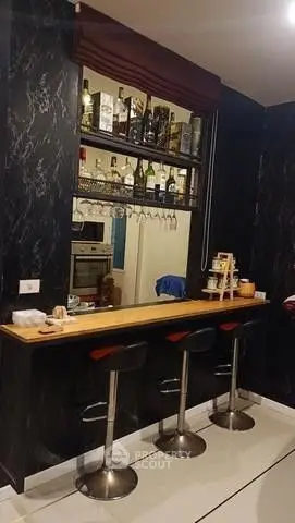 Chic home bar with stylish stools and elegant marble wall design, perfect for entertaining guests.