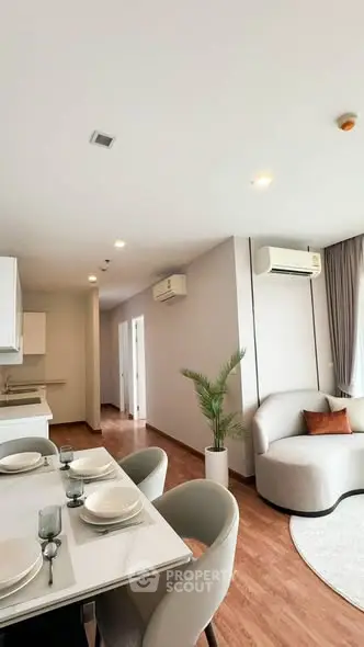 Modern living room with elegant dining area and cozy seating, featuring air conditioning and stylish decor.