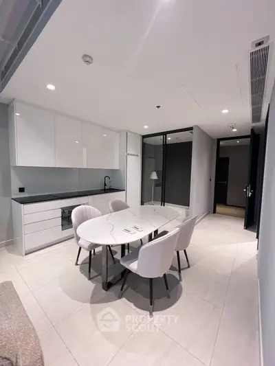 Modern kitchen with sleek white cabinets and elegant dining area in open layout.