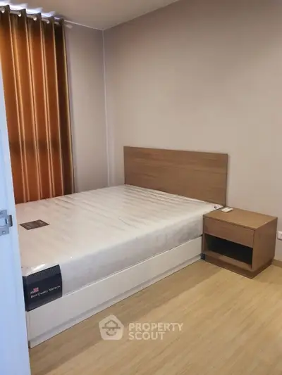 Cozy bedroom with wooden flooring and modern furnishings in a stylish apartment.