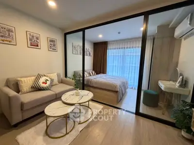 Modern studio apartment with cozy living area and stylish bedroom separated by glass partition.