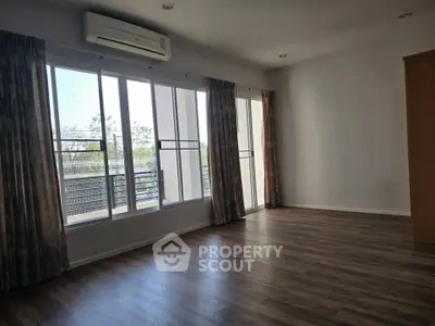 Spacious room with large windows and wooden flooring, perfect for natural light lovers.