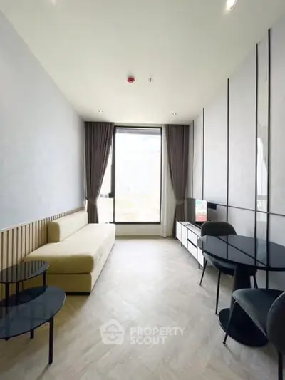 Modern living room with sleek furniture and large window offering natural light.
