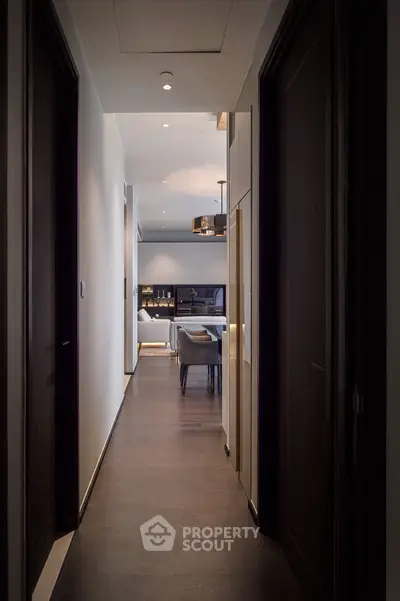 Elegant hallway leading to a modern living room with stylish furniture and ambient lighting.
