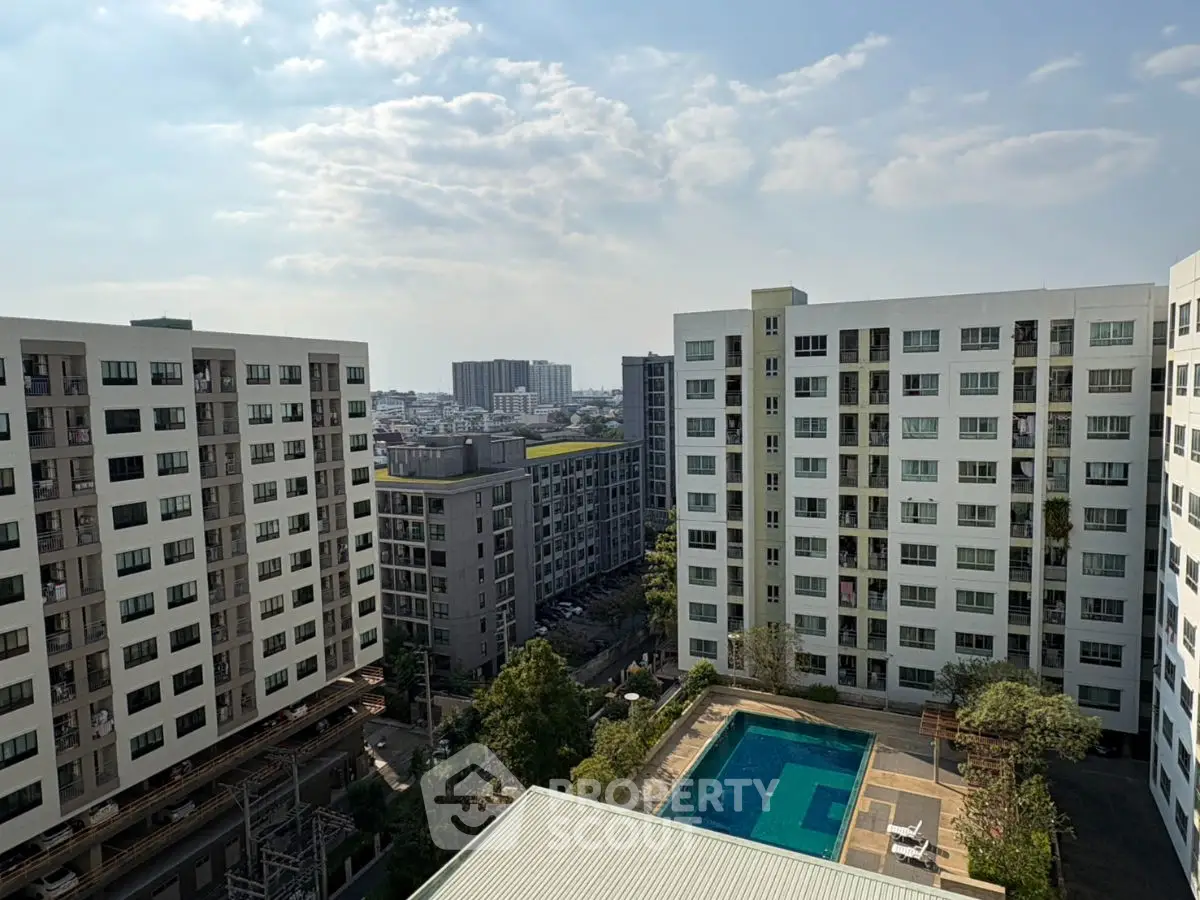 High-rise apartment buildings with a pool and city view under a clear sky.