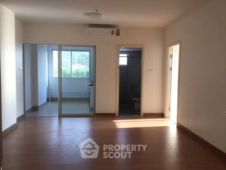 Spacious living room with wooden flooring and natural light in modern apartment.