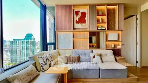Modern living room with stylish decor and city view, featuring a cozy sectional sofa and built-in shelving.