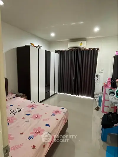 Cozy bedroom with modern furniture and air conditioning, featuring a stylish wardrobe and elegant curtains.