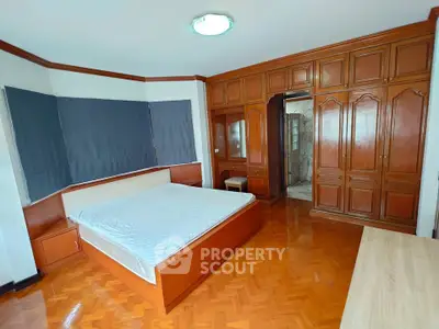 Spacious bedroom with wooden furniture and large built-in wardrobe