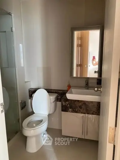 Modern bathroom with sleek fixtures and glass shower enclosure in a contemporary home.