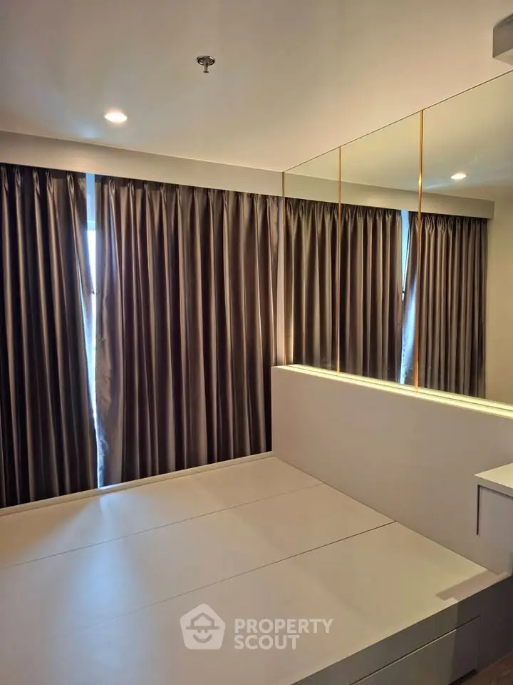 Modern bedroom with sleek design and large mirror reflecting natural light.