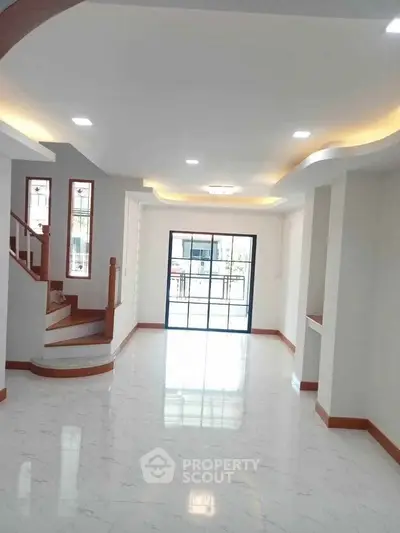 Spacious modern living room with elegant staircase and large windows