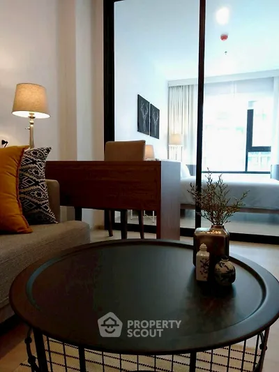 Modern living room with stylish decor and a glimpse into a cozy bedroom.