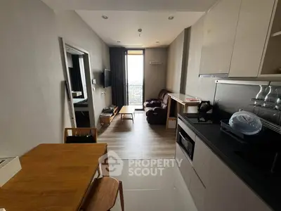 Modern apartment with open kitchen and cozy living area featuring sleek furniture and natural light.