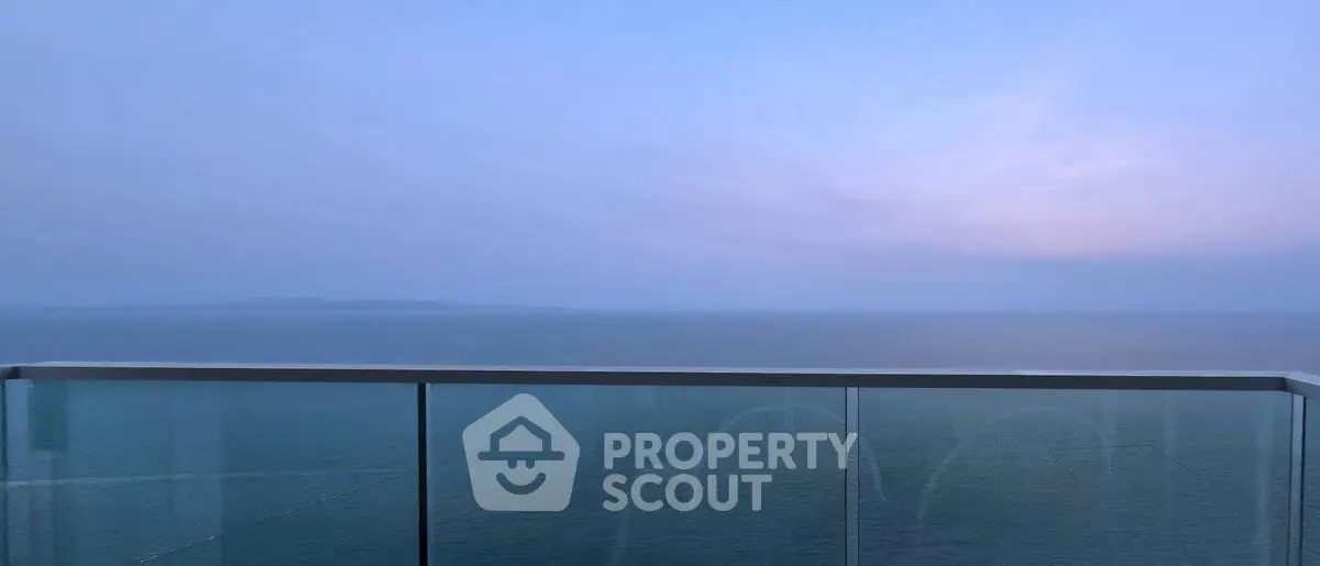 Stunning ocean view from a modern glass balcony at sunset.