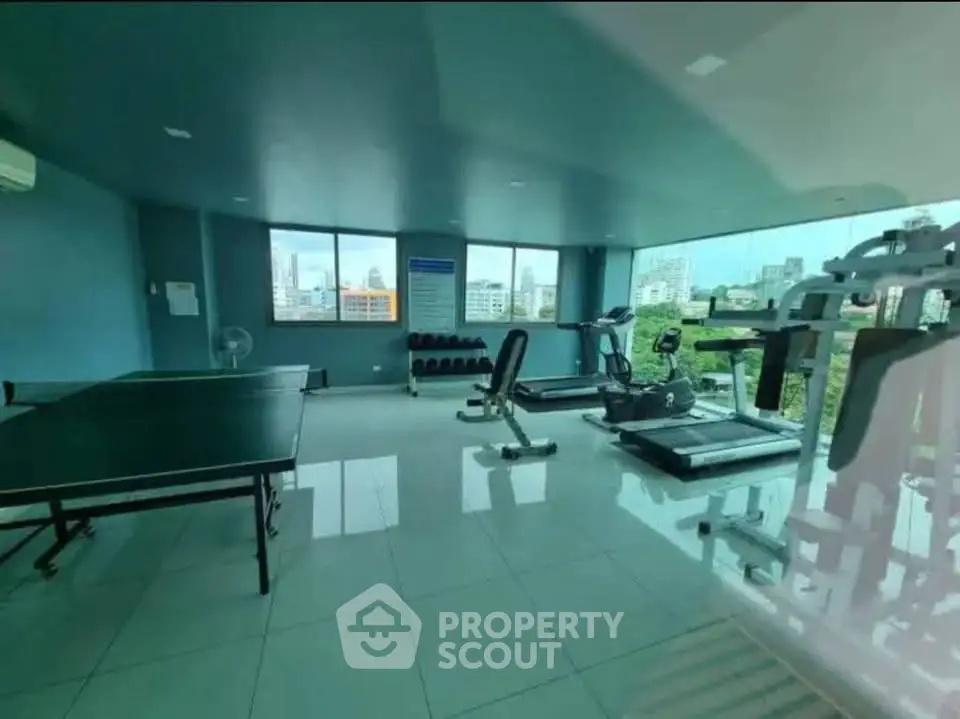 Spacious gym with modern equipment and city view in luxury apartment complex.