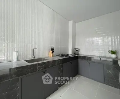 Modern kitchen with sleek design, featuring marble countertops and gas stove, perfect for culinary enthusiasts.