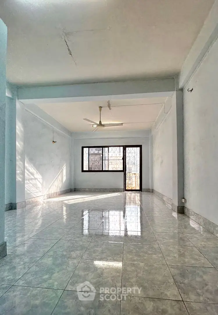 Spacious empty living room with large windows and ceiling fan