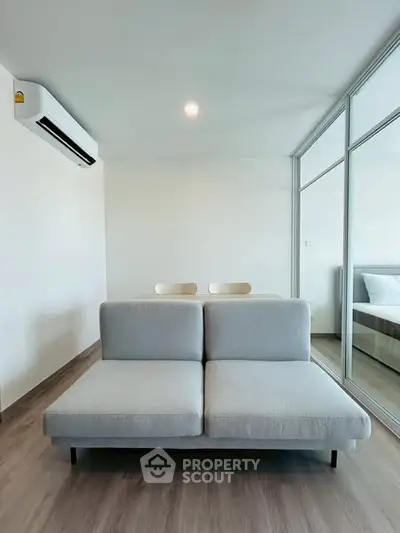 Modern minimalist living room with sleek furniture and mirrored closet doors.