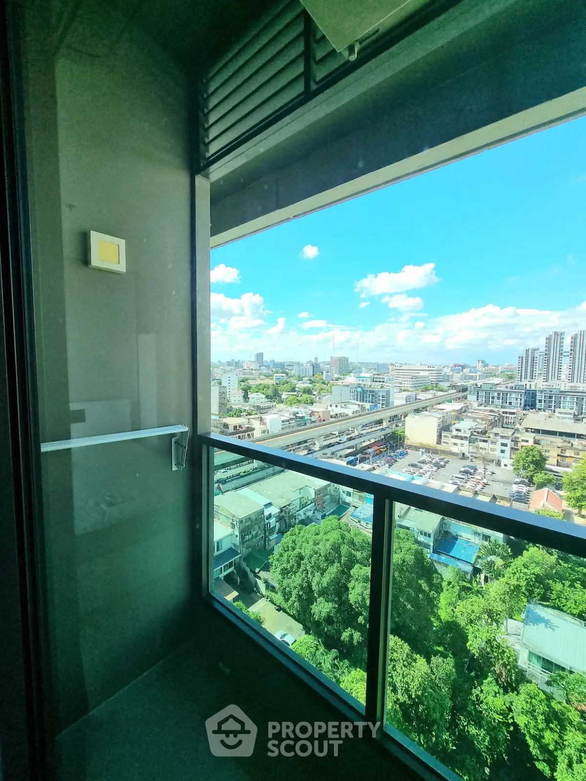 Stunning cityscape view from a modern balcony with glass railing, perfect for urban living.