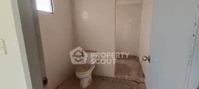 Spacious bathroom with tiled floor and open shower area, ideal for renovation.