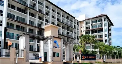 Modern multi-story residential building with lush palm trees and gated entrance.