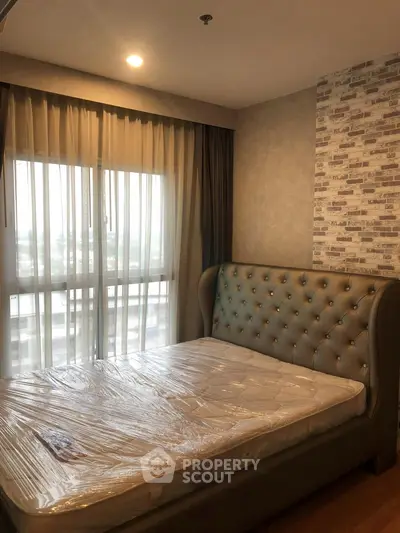Modern bedroom with stylish upholstered bed and large window with sheer curtains.
