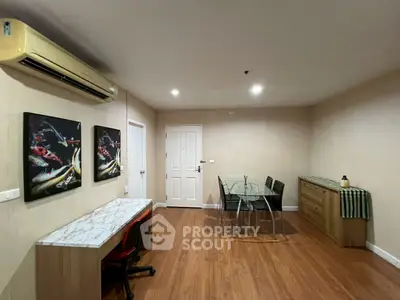 Spacious living room with modern decor and wooden flooring, featuring a dining area and stylish artwork.