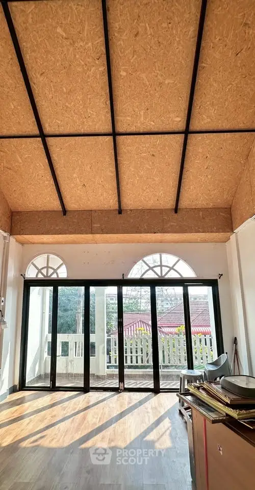 Spacious room with high ceiling and large windows offering natural light and scenic view.